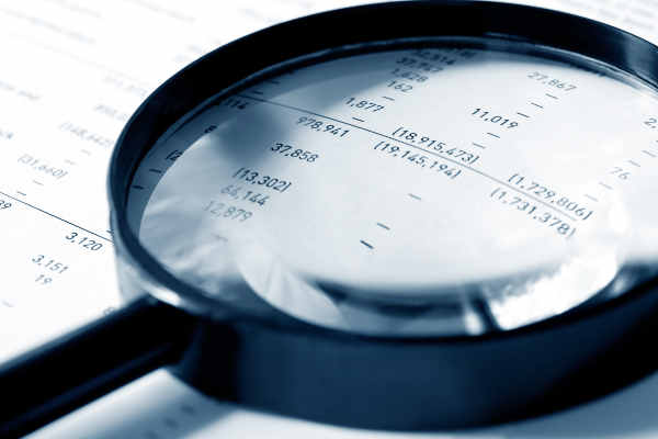 Magnifying glass over financial figures. Shallow DOF, cyan tone.